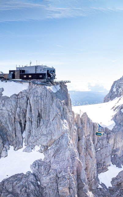 Panoramablick auf die Dachstein-Gletscherbahn und die markante Bergstation auf dem schneebedeckten Berg | © Josh Absenger