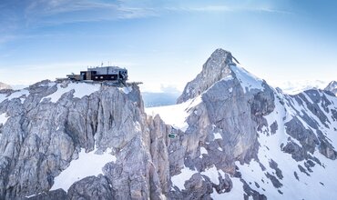 Panoramablick auf die Dachstein-Gletscherbahn und die markante Bergstation auf dem schneebedeckten Berg | © Josh Absenger