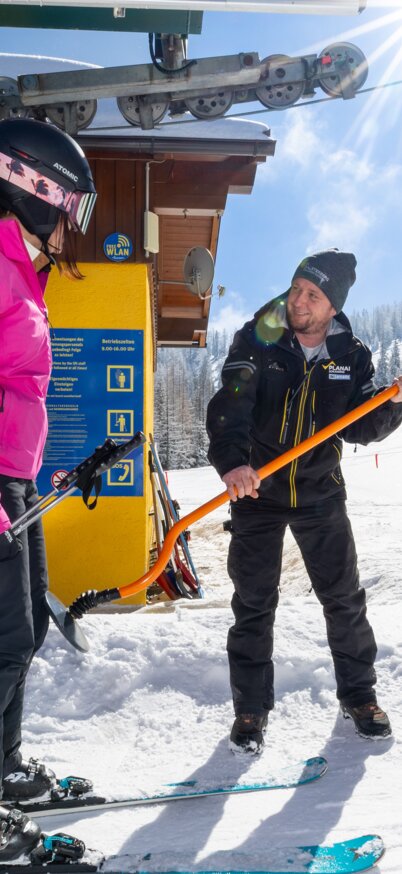 Eine Skifahrerin an einem Tellerlift; ein Mitarbeiter hilft ihr beim Einsteigen | © Harald Steiner 
