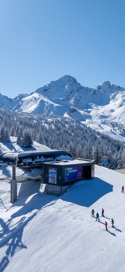 endering der neuen Senderbahn am Hauser Kaibling im Winter, eingebettet in eine verschneite Berglandschaft mit Skifahrern im Vordergrund und eindrucksvollem Panorama der Schladminger Tauern im Hintergrund.. | © Josh Absenger
