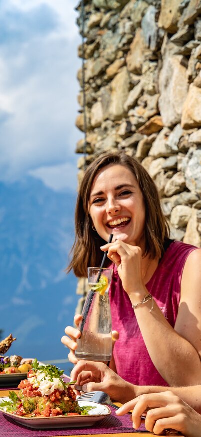 Zwei Frauen genießen regionale Schmankerl und Getränke auf der Terrasse des Schutzhaus Kaiblingalm mit Bergblick. | © Nolis und Sabrina Vanray