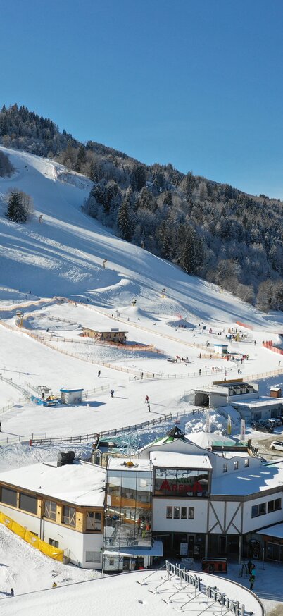 Hauser Kaibling valley station photographed from above with a drone. Wollis Kids Park, AlmArenA, parking lot, the village of Haus and the 8-seater gondola lift can be seen. | © Hauser Kaibling