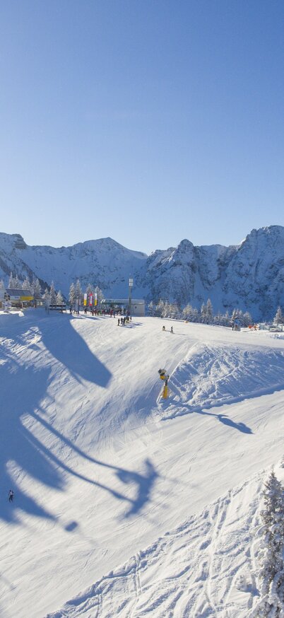 Luftaufnahme vom Senderplateau am Hauser Kaibling. Drei Seilbahnen, breite Pisten mit Skifahrern und eine verschneite Winterlandschaft. | © Josh Absenger