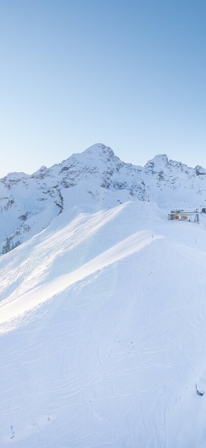 Panorama of the snow-covered Hauser Kaibling with the rising sun behind the mountains. | © Josh Absenger
