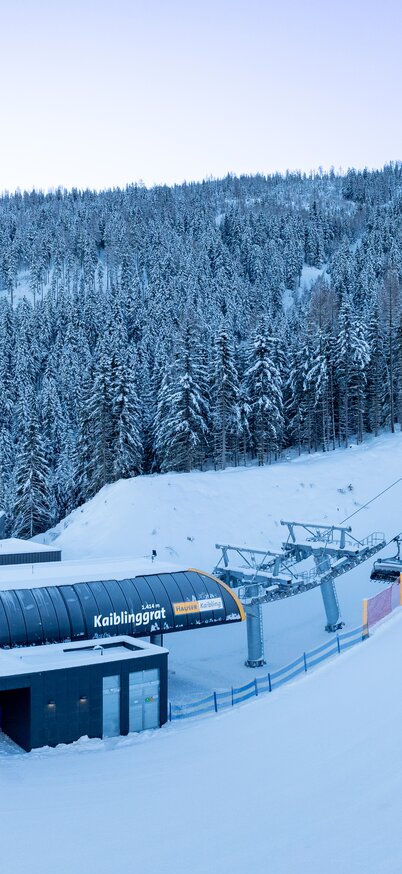 Valley station of the new 8-seater Kaiblinggrat chairlift in the middle of snow-covered forests at Hauser Kaibling. | © Josh Absenger