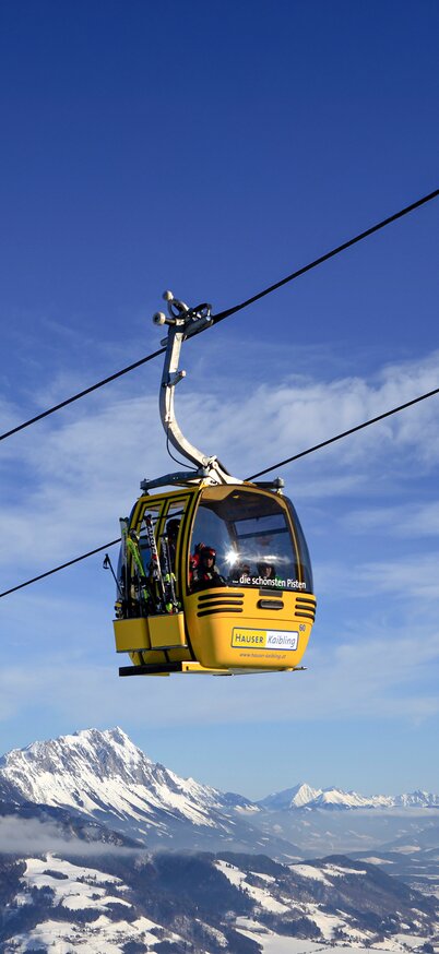Gelbe Gondeln der Hauser Kaibling Seilbahn schweben vor beeindruckender Bergkulisse über das Ennstal. | © Hauser Kaibling