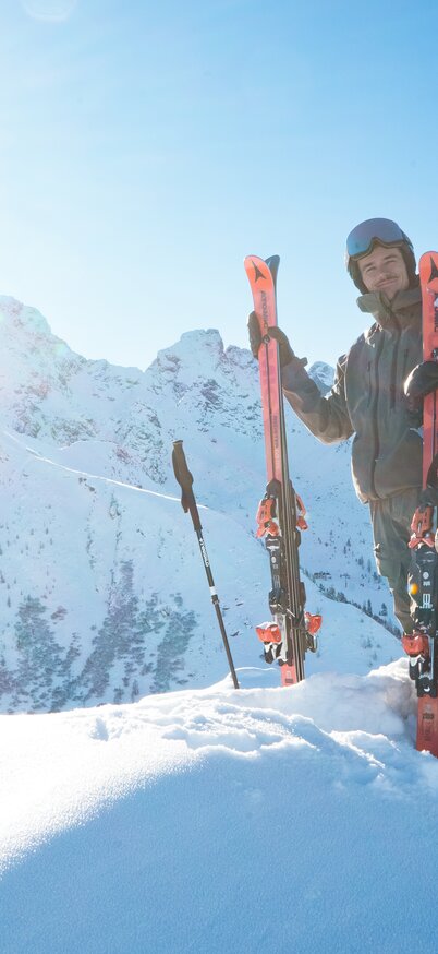 Zeit zu zweit am höchsten Punkt der 4-Berge-Skischaukel Schladming, den Hauser Kaibling Gipfel, genießen | © Josh Absenger Ein Skifahrer und eine Skifahrerin posieren am Gipfel des Hauser Kaibling mit Skiern in der Hand vor beeindruckendem Bergpanorama. | © Josh Absenger