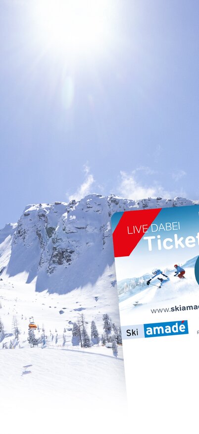 Two ski tickets in front of a snow-covered mountain landscape with chairlift and sunshine. | © Hauser Kaibling