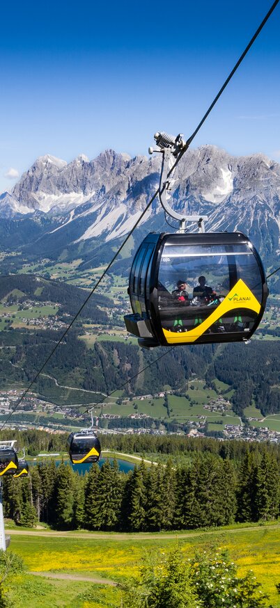 Die Planai Hauptseilbahn bei traumhaftem Sommerwetter - im Hintergrund das Dachsteinmassiv | © Josh Absenger