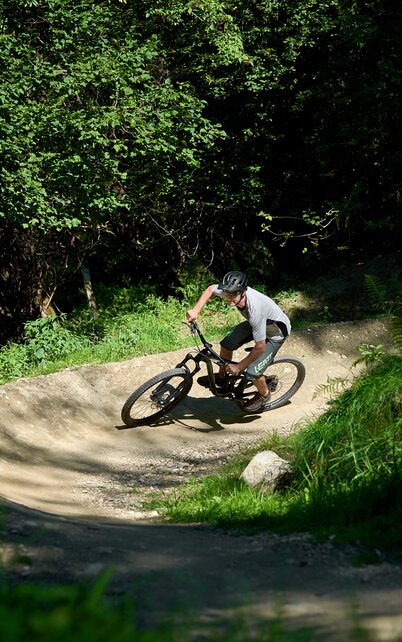Ein Biker fährt in Schräglage durch eine Anliegerkurve der Stadium Flowline im schattigen Wald von Schladming. | © Dietmar Koerbler