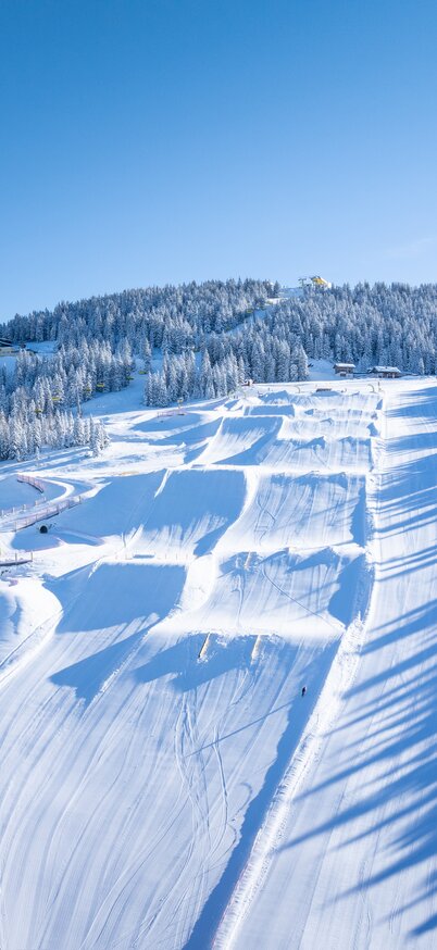 Drohnenaufnahme mit Blick auf den Superpark Planai und die Märchenwiesebahn Talstation | © Josh Absenger