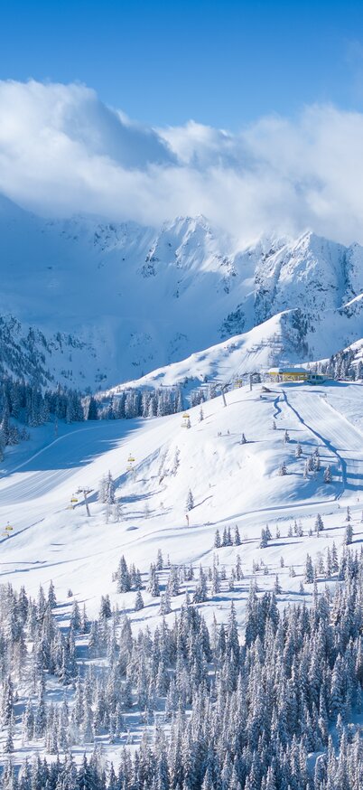 Verschneites Skigebiet Mitterhaus auf der Planai mit präparierten Pisten und Sessellift | © Josh Absenger