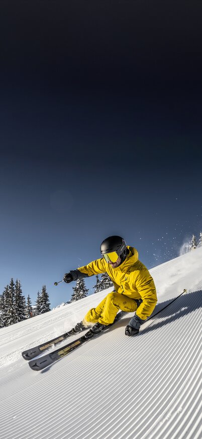 Ein Skifahrer zieht genussvoll seine Kurven in den Schnee | © Mirja Geh
