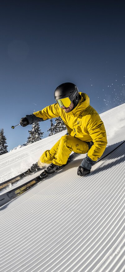 Sonneskilauf vom Feinsten auf der Planai | © Mirja Geh Ein Skifahrer zieht genussvoll seine Kurven in den Schnee | © Mirja Geh