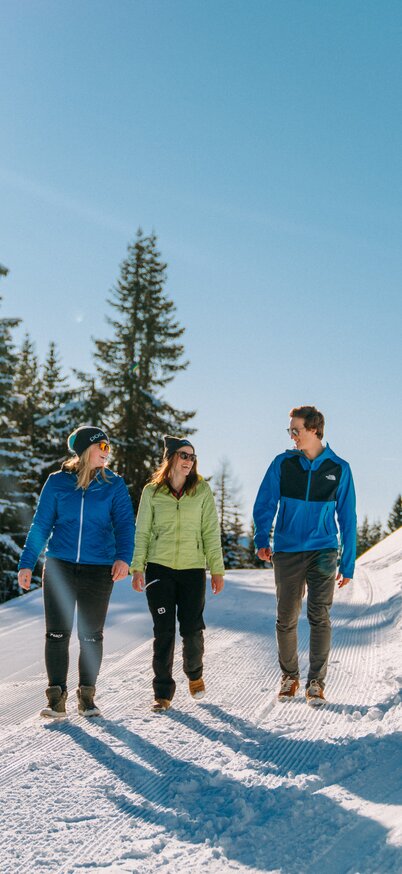 Winterwandern auf der Planai in Schladming | © Christine Höflehner Drei Freunde beim Winterwandern auf der Planai am Winter Wander Weg inmitten der idyllischen Winterlandschaft | © Christine Höflehner