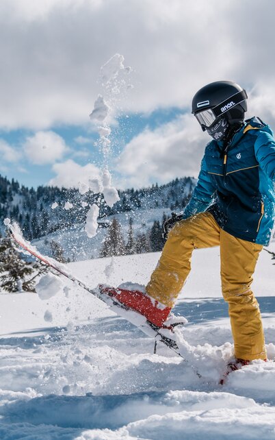 Kind wirft mit dem Ski Schnee in die Luft. | © Gerald Grünwald