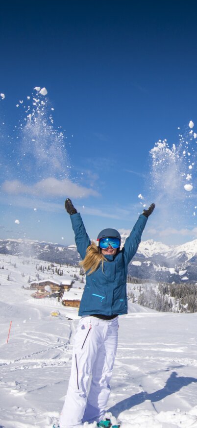 Skifahrerin steht auf der Piste der Fageralm und schmeißt Schnee in die Höhe. | © Lorenz Masser