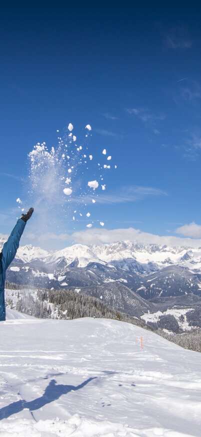 Skifahrerin steht auf der Piste der Fageralm und schmeißt Schnee in die Höhe. | © Lorenz Masser
