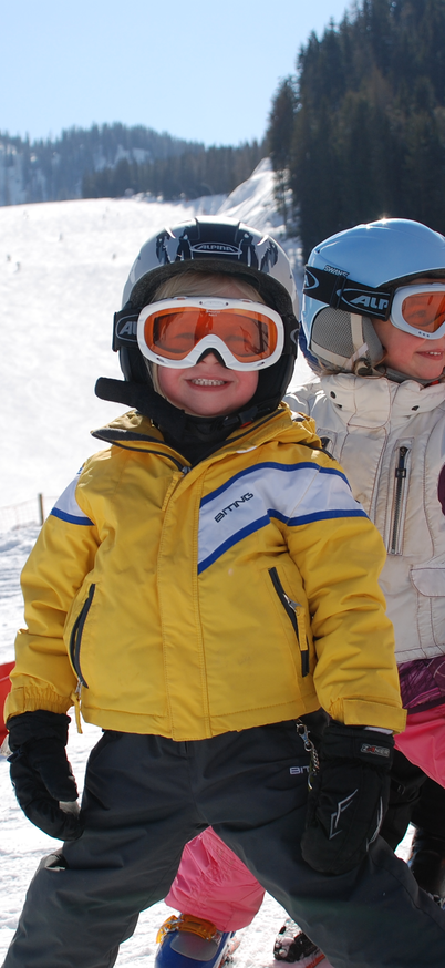 3 Kinder, glücklich lächelnd, stehen im Pflug hintereinander im Kinderland Reiteralm.  | © Reiteralm Bergbahnen
