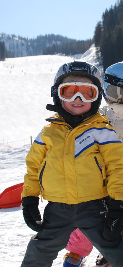 3 Kinder, glücklich lächelnd, stehen im Pflug hintereinander im Kinderland Reiteralm.  | © Reiteralm Bergbahnen
