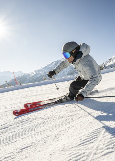 Skifahrer fährt bei Sonnenschein die Piste der Reiteralm hinunter. | © Lorenz Masser