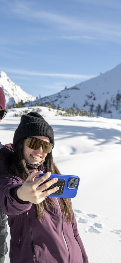 Ein Pärchen steht im Schnee auf der Reiteralm und macht ein Selfie. | © Lorenz Masser