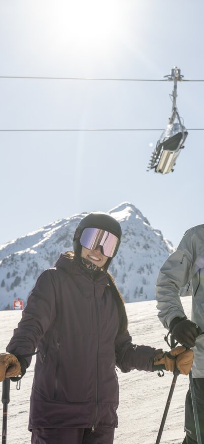 2 Skifahrer stehen auf der bestens präparierten Piste der Reiteralm. Im Hintergrund fährt ein Sessel der Schoberbahn. | © Lorenz Masser