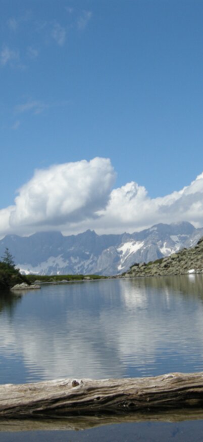 Spiegelsee auf der Reiteralm mit Spiegelung vom Dachstein Dreigestein und wunderschöner Aussicht auf die Berge.