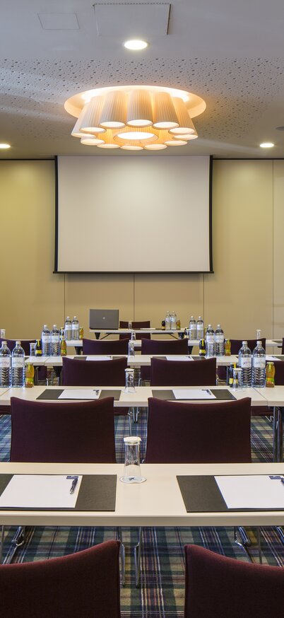 Seminarraum gedeckt mit Notizblöcke, stifte und Getränke, Flipchart und Leinwand | © Hotel Falkensteiner Schladming