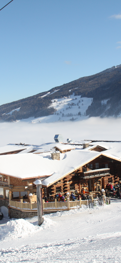 Skihütte mit Schneebedeckt mit vielen Skifahrer auf der Terasse bei schönem Wetter. | © Tauernalm