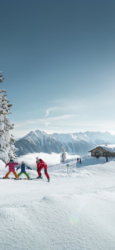 Kinder fahren einem Skilehrer nach umgeben von einer traumhaften Bergwelt | © Peter Burgstaller