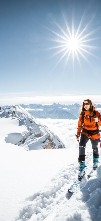 Eine Skitourengeherin, welche sich bei Sonnenschein bergauf fortbewegt im Hintergrund sieht man die Seethalerhütte | © Mathäus Gartner