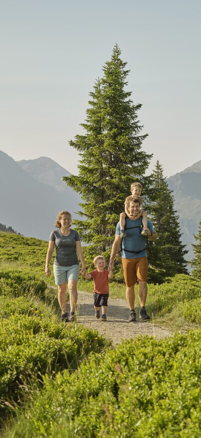 Familie spaziert auf der Planai auf einem schmalen Weg Hand in Hand. | © Peter Burgstaller
