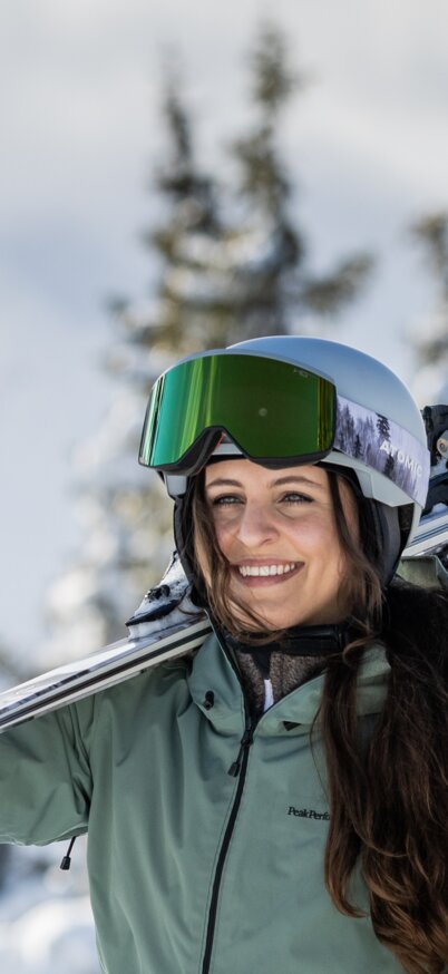 Skifahrerin trägt Ski und lacht | © Mirja Geh