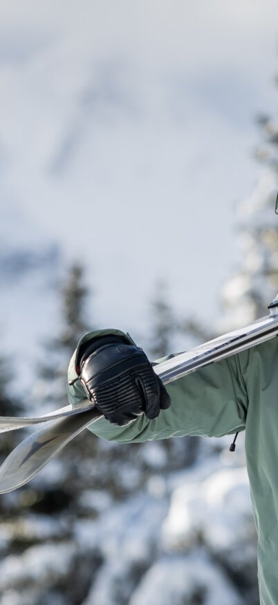 Skifahrerin trägt Ski und lacht | © Mirja Geh