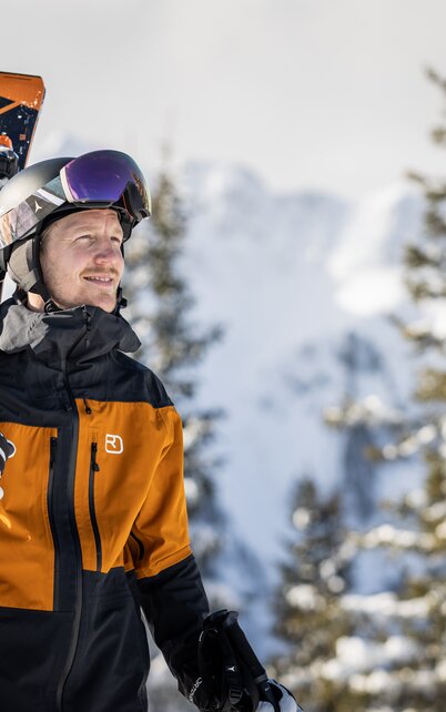 Skifahrer trägt Ski und lacht | © Mirja Geh