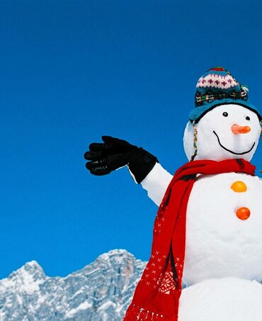 Schneemann vor der Kulisse des Dachstein-Massiv